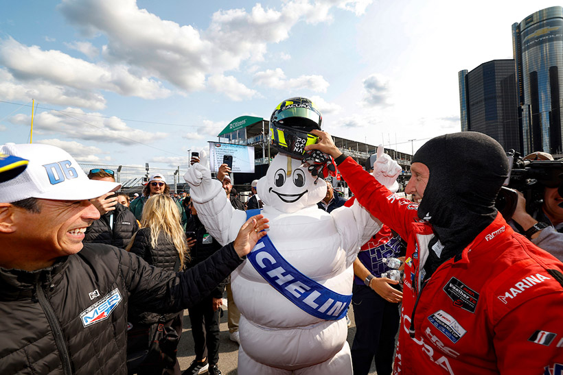 #93: Acura Meyer Shank Racing w/Curb Agajanian, Acura ARX-06, GTP: Renger van der Zande, puts his helmet on Michelin Man as Helio Castroneves watches